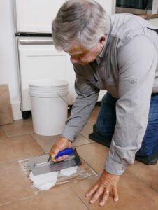 After removing a broken tile, Tom spreads a premixed acrylic tile adhesive, a.k.a. mastic.