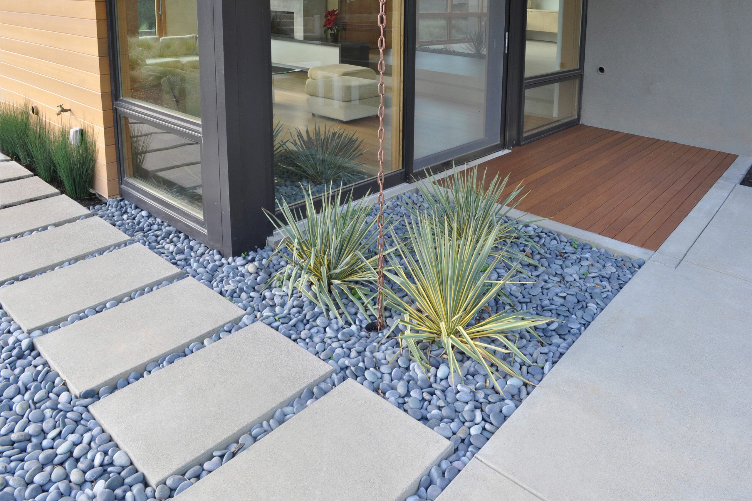 A house uses river rocks to landscape around the patio.