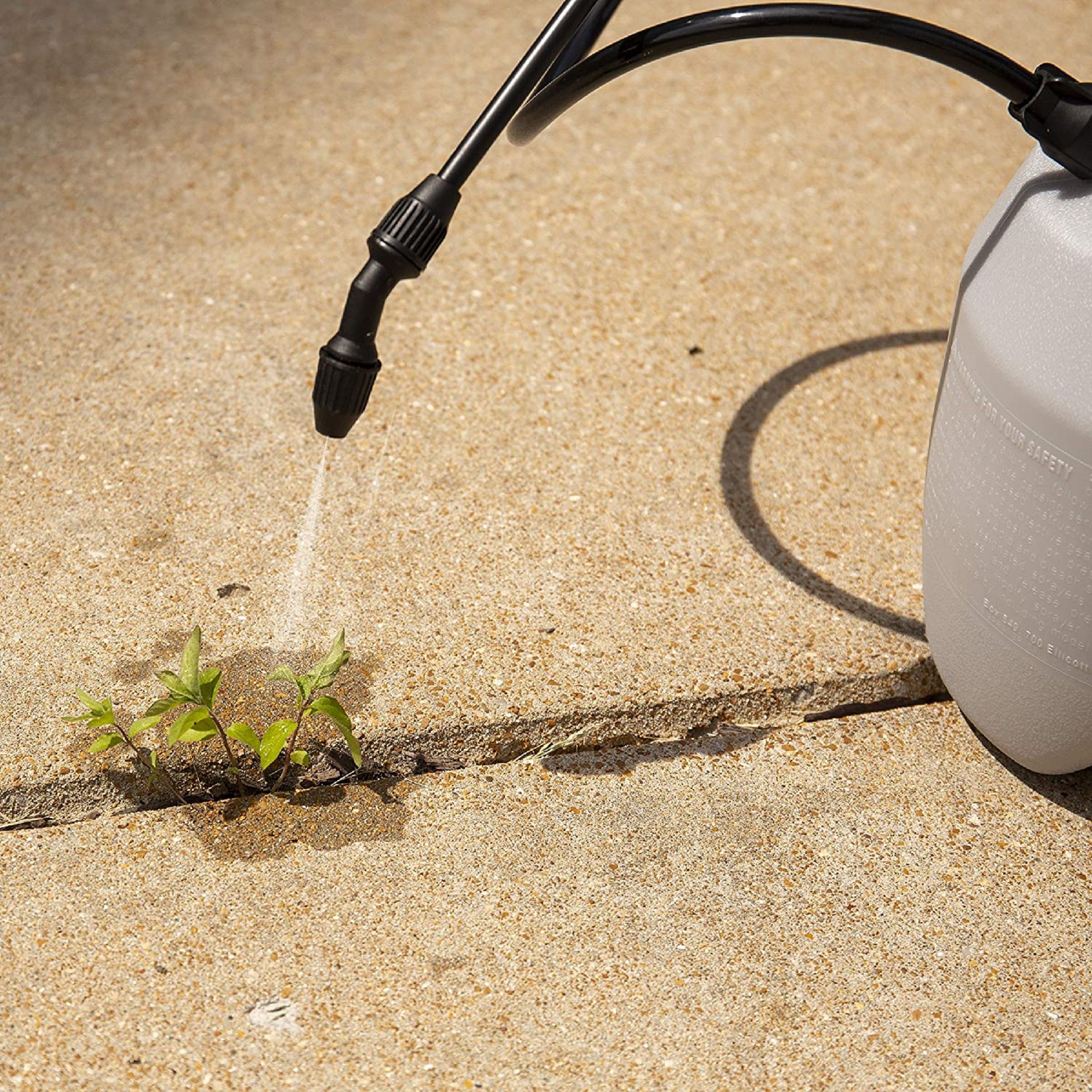 Image of an herbicide being sprayed onto a weed in a sidewalk crevice. Cover image for This Old House's Best Weed Killer Guide and Product Review.