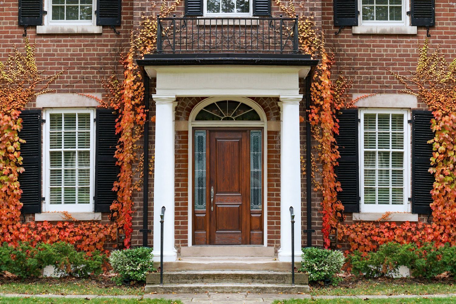 The front of a brick home on a Fall day.