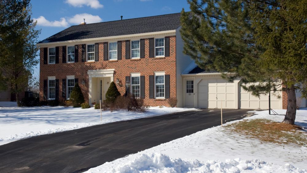 Snowy house with a driveway kept clear by a heated driveway system.