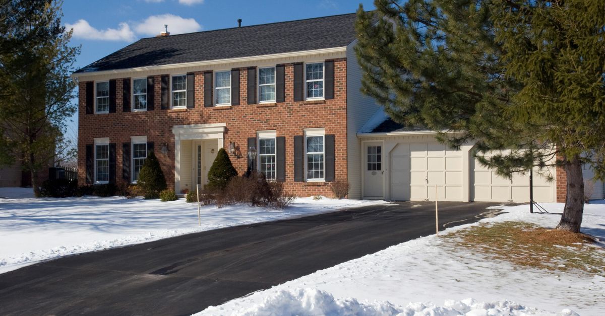 Snowy house with a driveway kept clear by a heated driveway system.