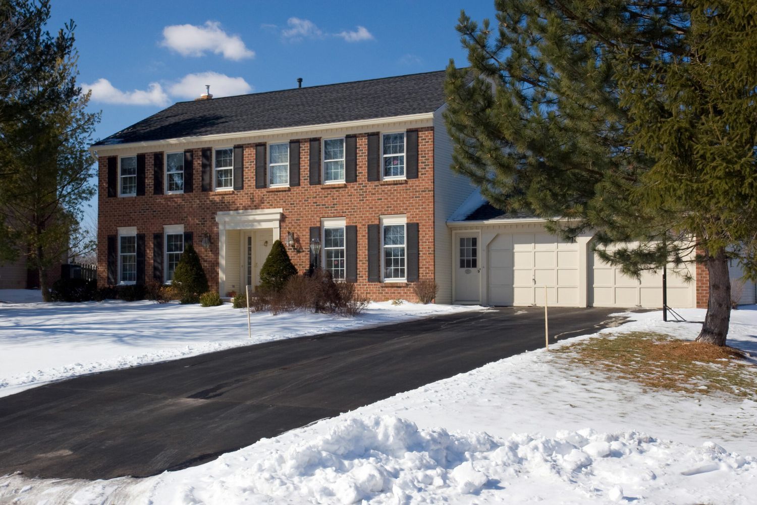 Snowy house with a driveway kept clear by a heated driveway system.
