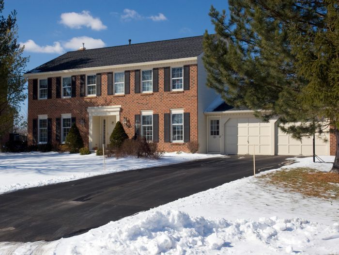 Snowy house with a driveway kept clear by a heated driveway system.