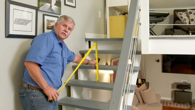 A man using a measuring tape to measure the vertical distance between two steps.