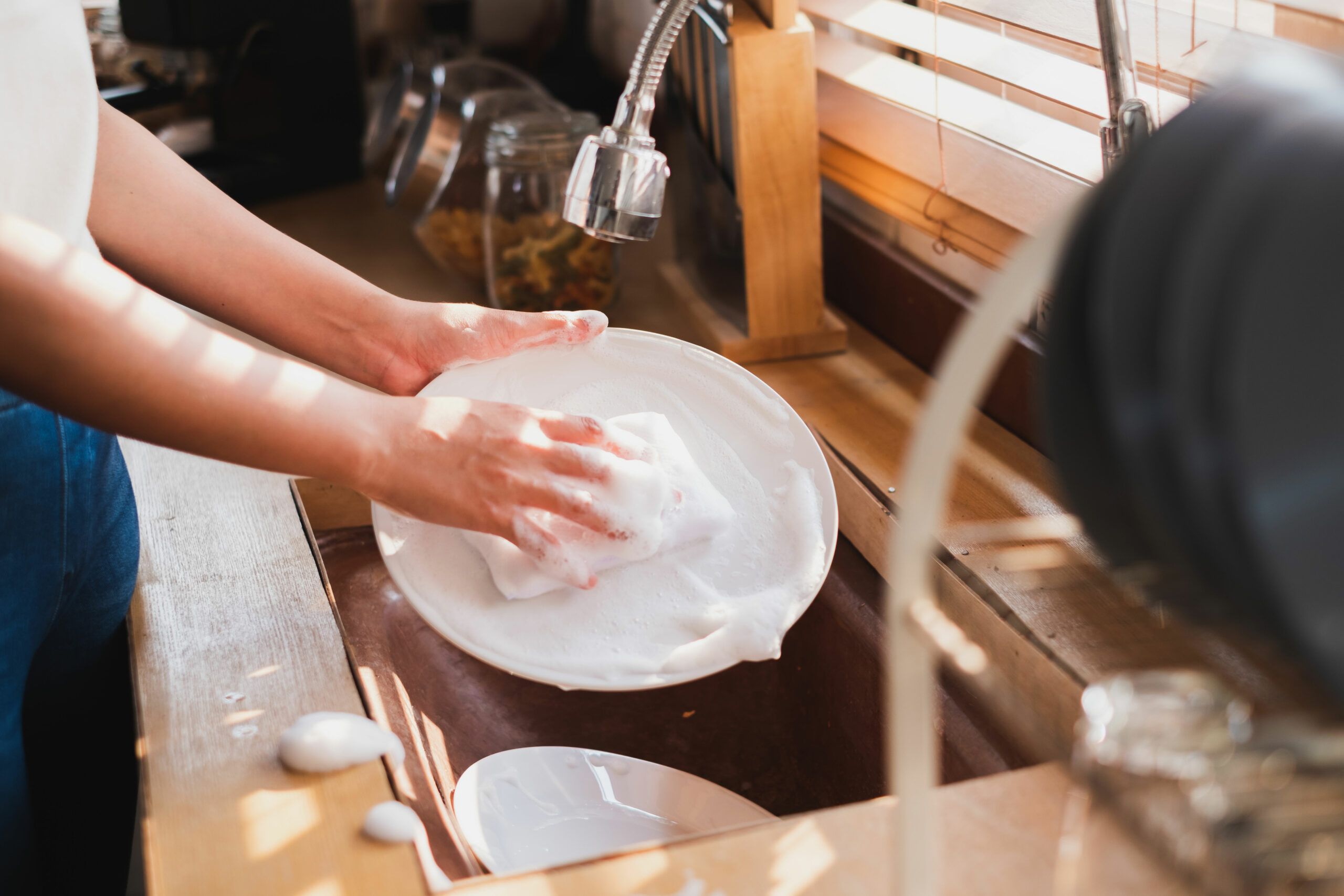 A person cleaning a dish with dish soap.