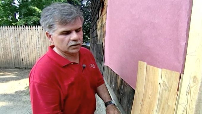 A man standing in front of a houses shingle siding.