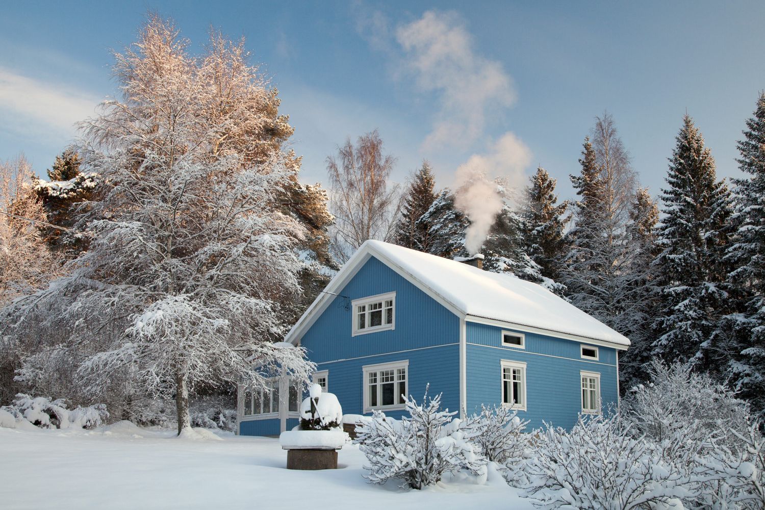 A house covered in snow with a chimney and chimney flue.