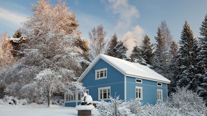 A house covered in snow with a chimney and chimney flue.