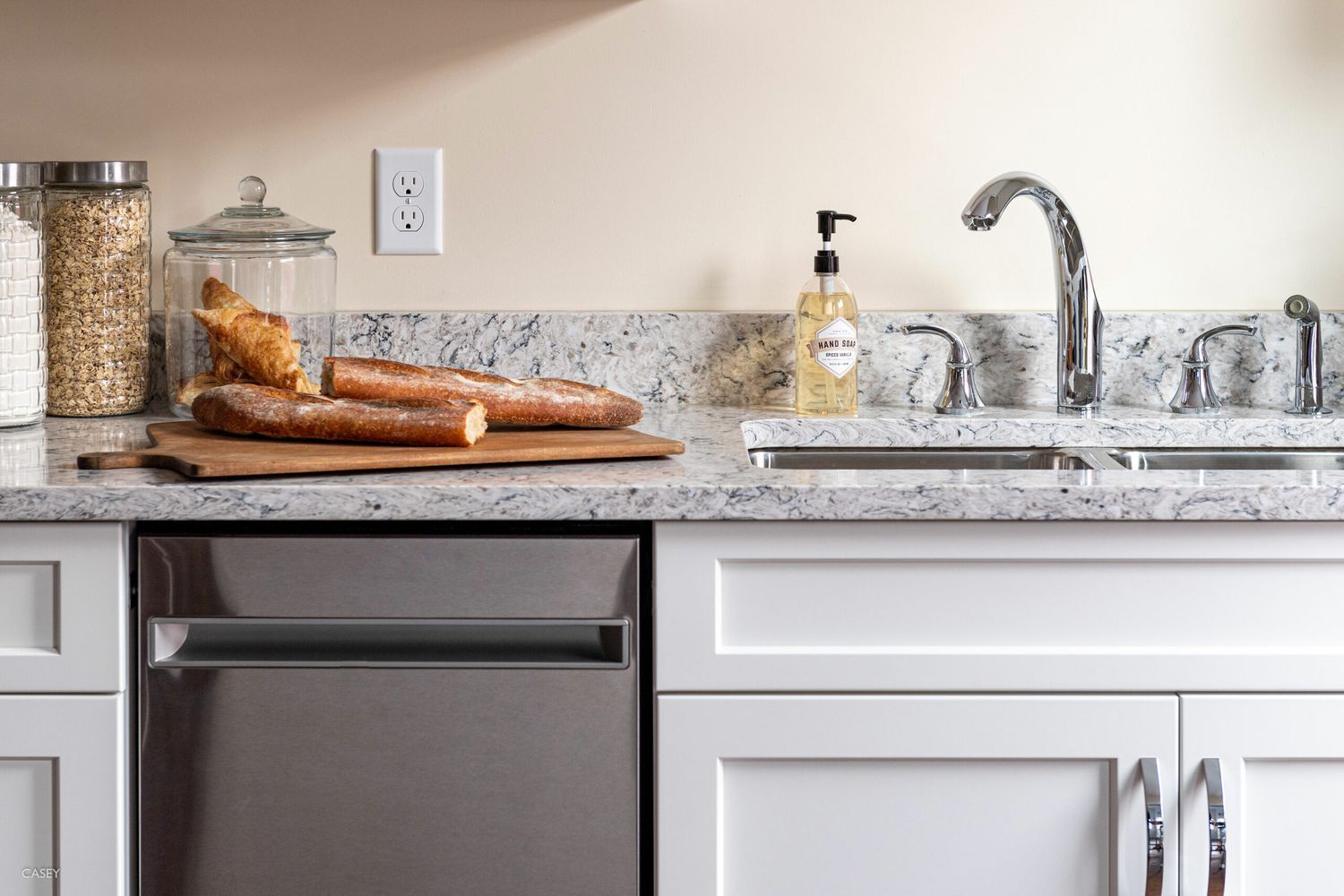A decluttered kitchen with a sink and a cutting board with bread on top of it.