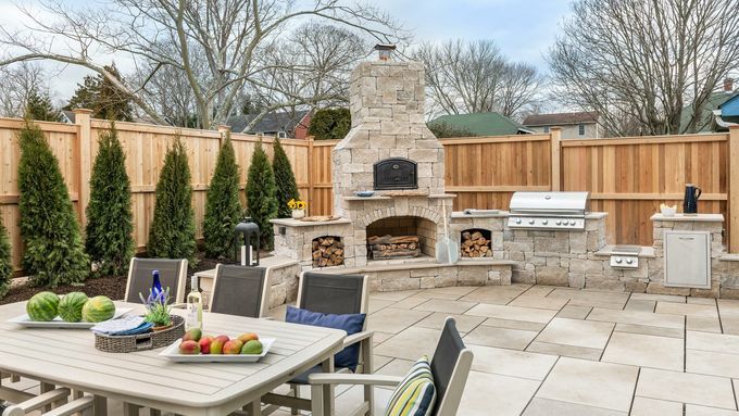 Back yard patio with grill, table, and fireplace.