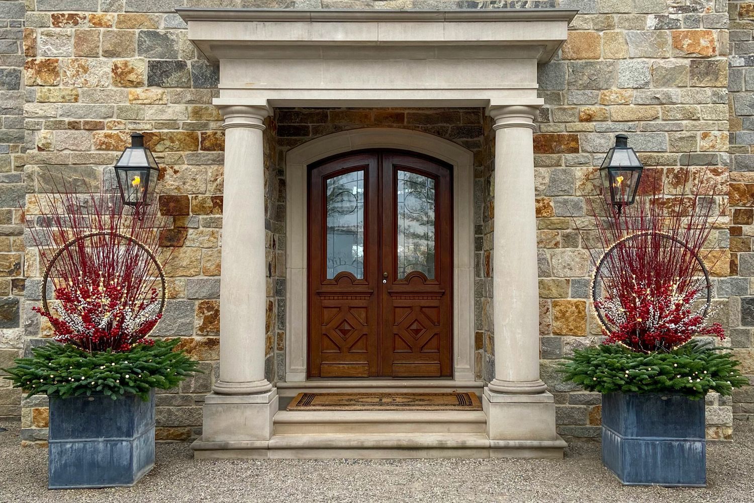 The front door of a building with a pair of winter plants in containers on either side.