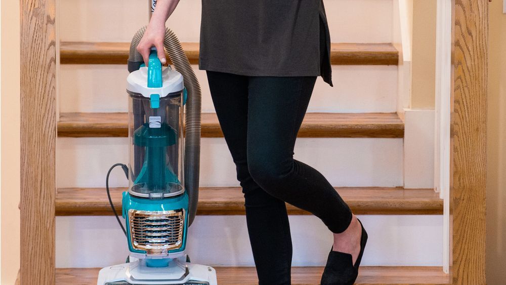 woman holding Kenmore upright vacuum while walking down stairs in a home