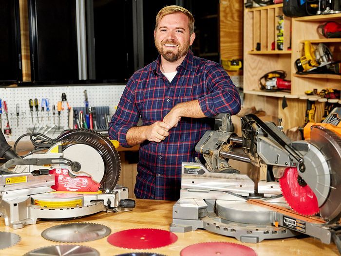 A man showing off different types of miter saw blades.