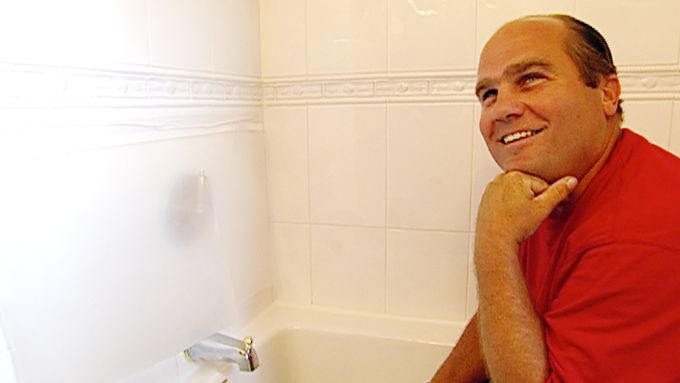 A man sitting in a tub with his hand against his chin.