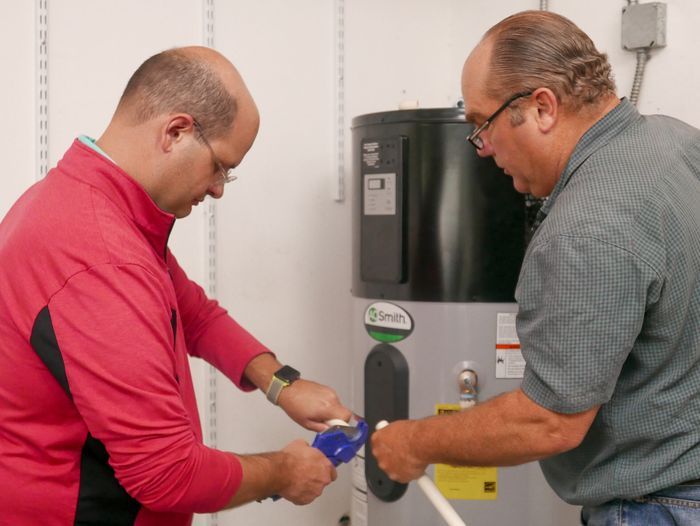 Two professionals plumbers installing a heat pump water heater