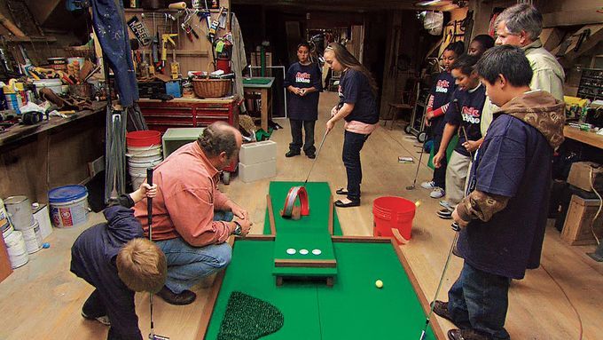 A group of people playing miniature golf on a homemade course.