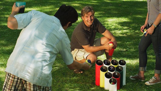 A man throwing a ball towards a set of pipes in a pipe ball lawn game.