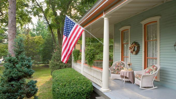 an American flag hanging outside a house in preparation for the fourth of july