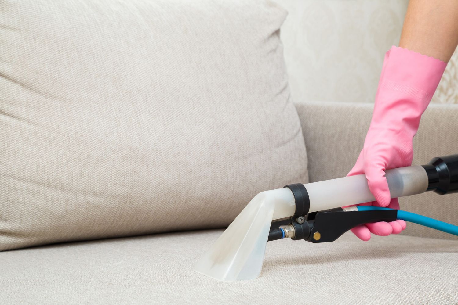 A person using a vacuum to remove smoke odor from upholstery.