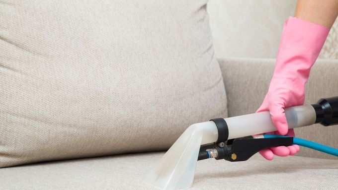 A person using a vacuum to remove smoke odor from upholstery.