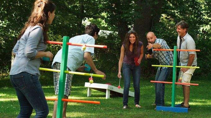 A group of people playing with a ladder golf game set in a yard