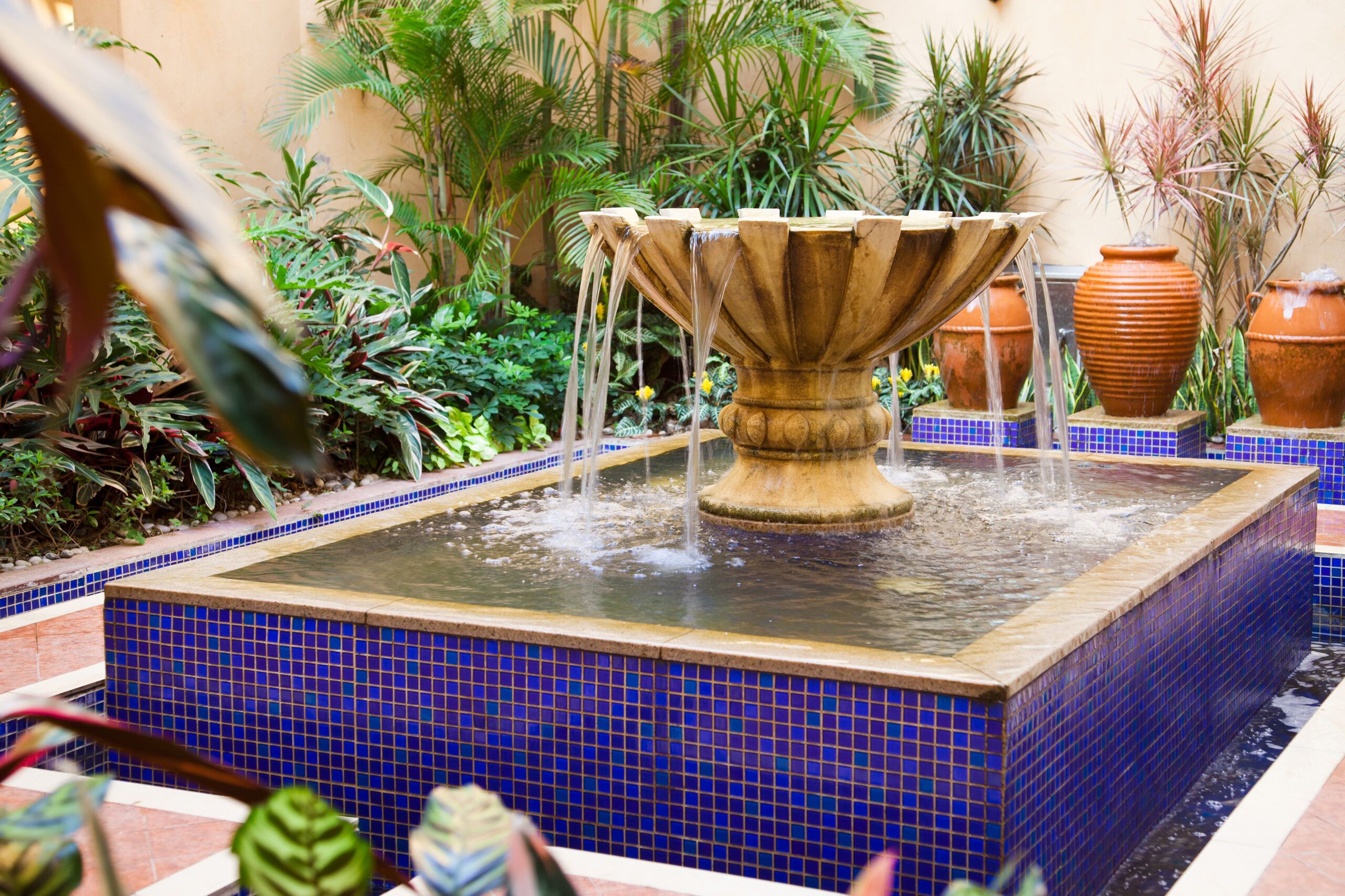 Large fountain in the middle of the patio with blue tile.