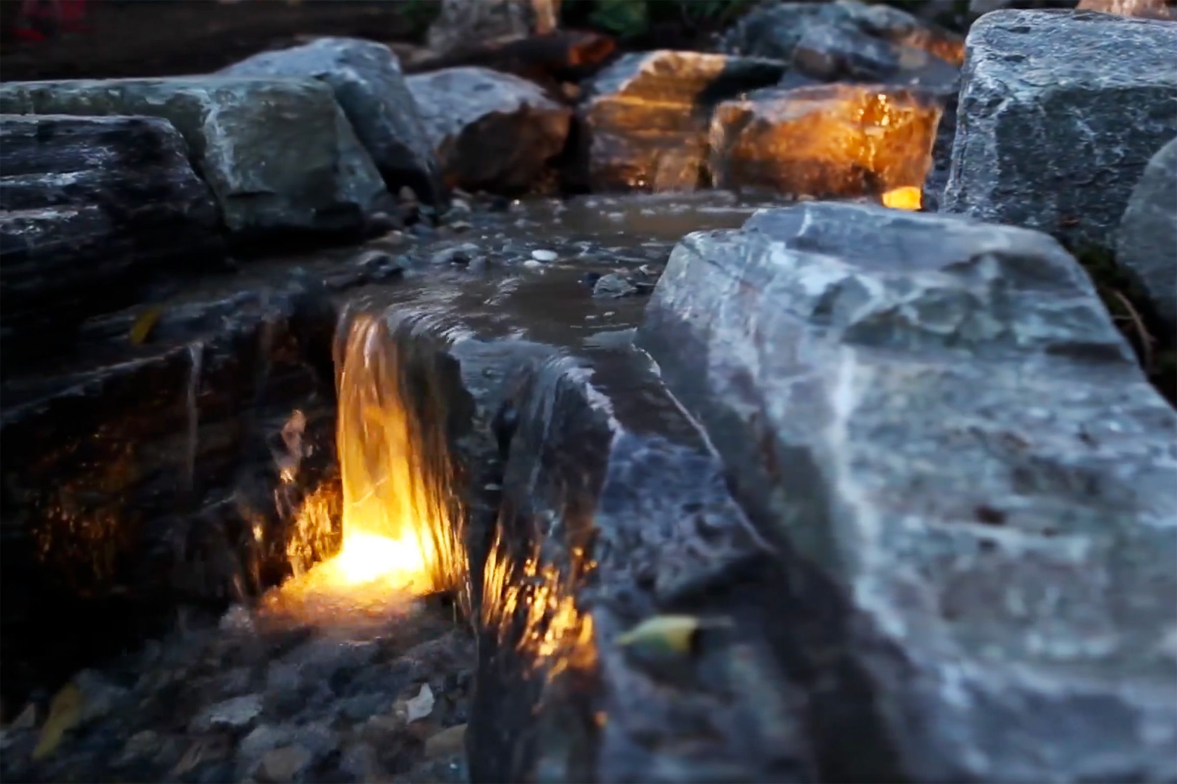 Pond less waterfall with rocks and yellow light.