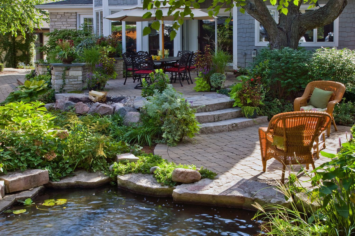 a backyard with a pond, many plants and furniture
