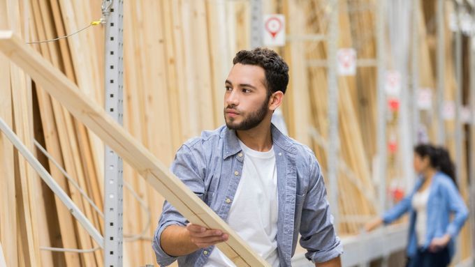 A man at a lumber store looking at a board of wood.