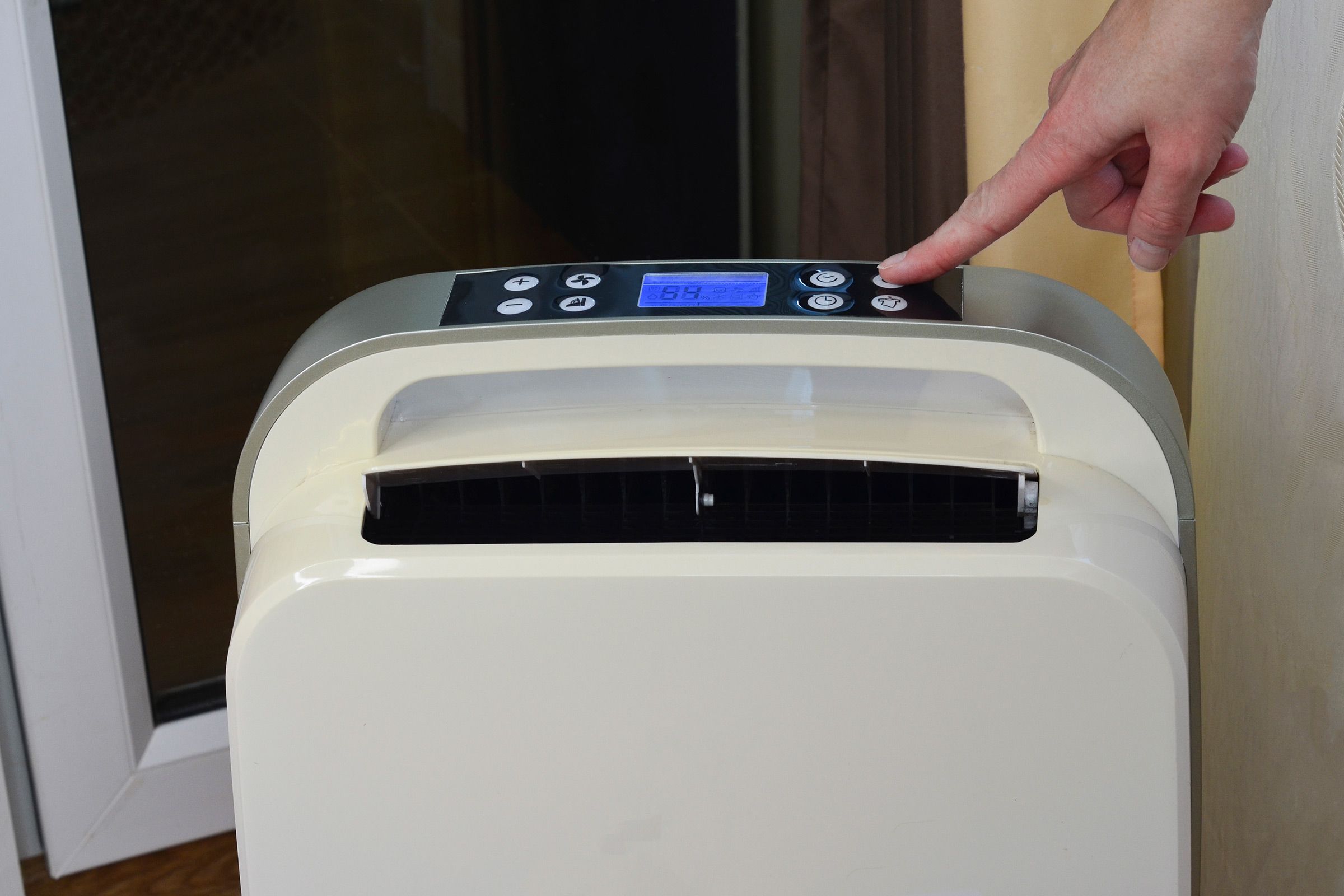 A person pressing a button on their air conditioning unit.