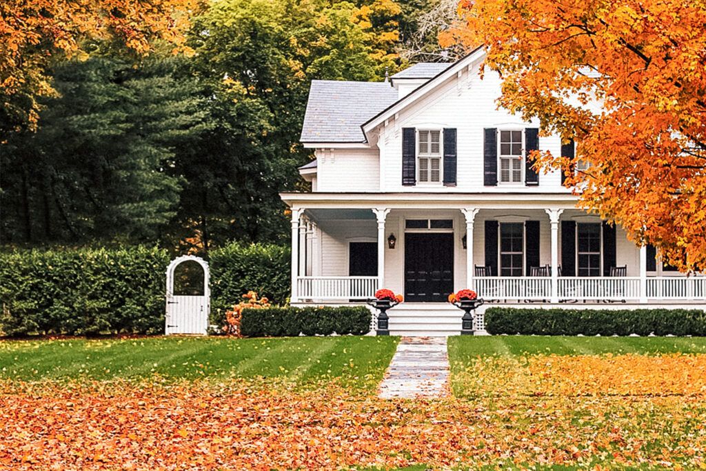 White house with leaves on the lawn in fall