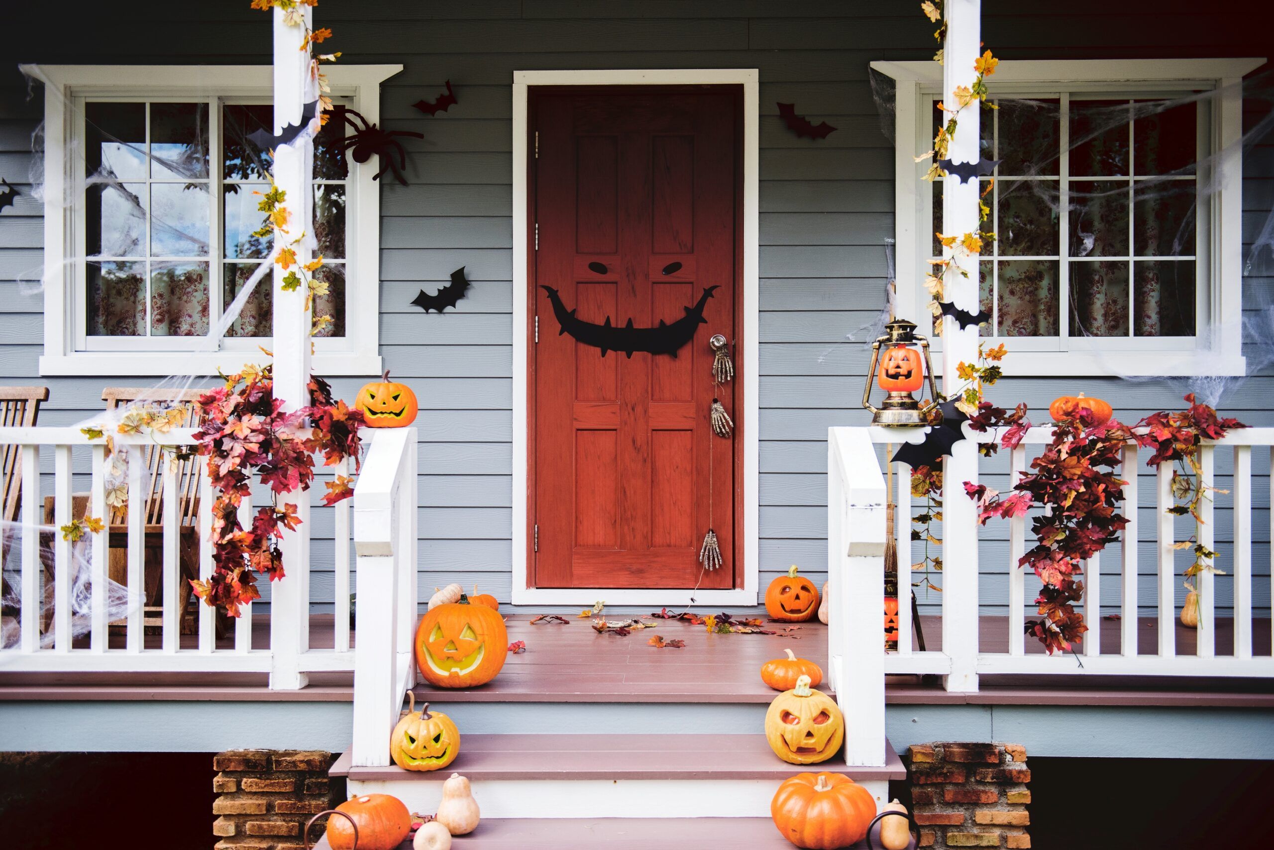 Best Spooky Decor for Halloween - jack-o-lanterns, fall leaves, and other Halloween decorations on front porch of a house