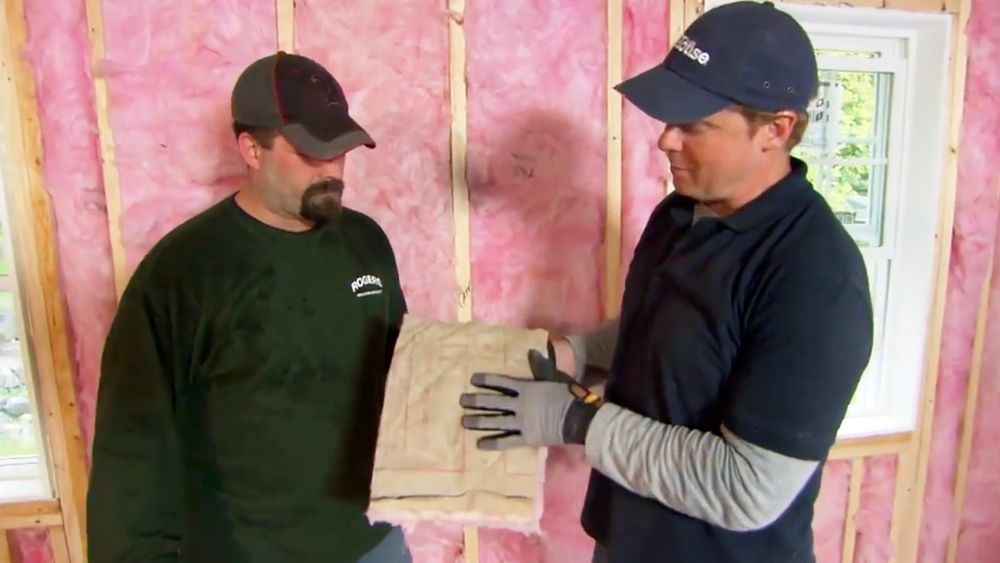 Two men installing fiberglass insulation