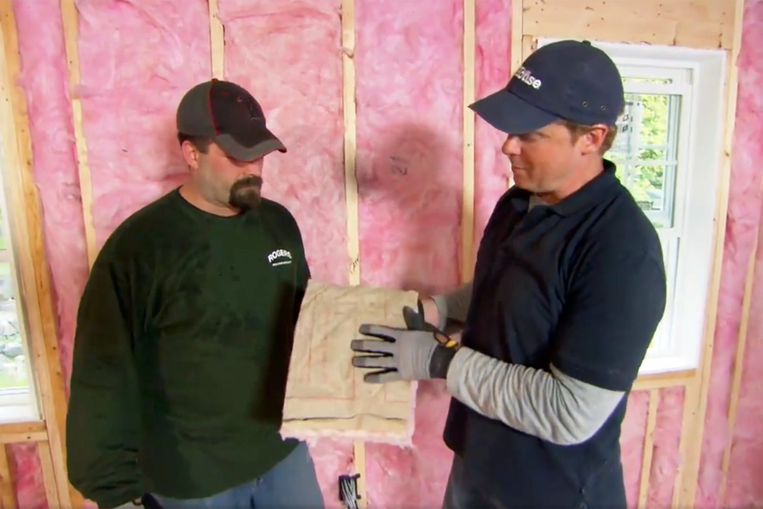 Two men installing fiberglass insulation