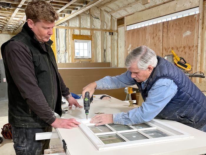 S44 E24, Kevin O'Connor assists Tom Silva with installing a new window sash in the entry door of the garage