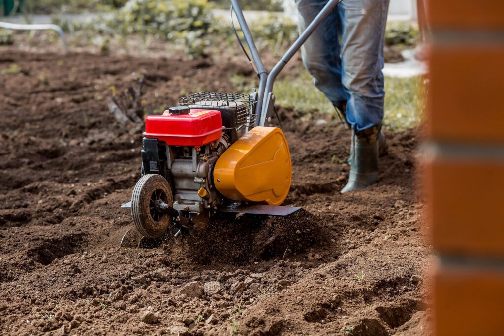 Farmer plows the land with a cultivator. Tillage in the garden