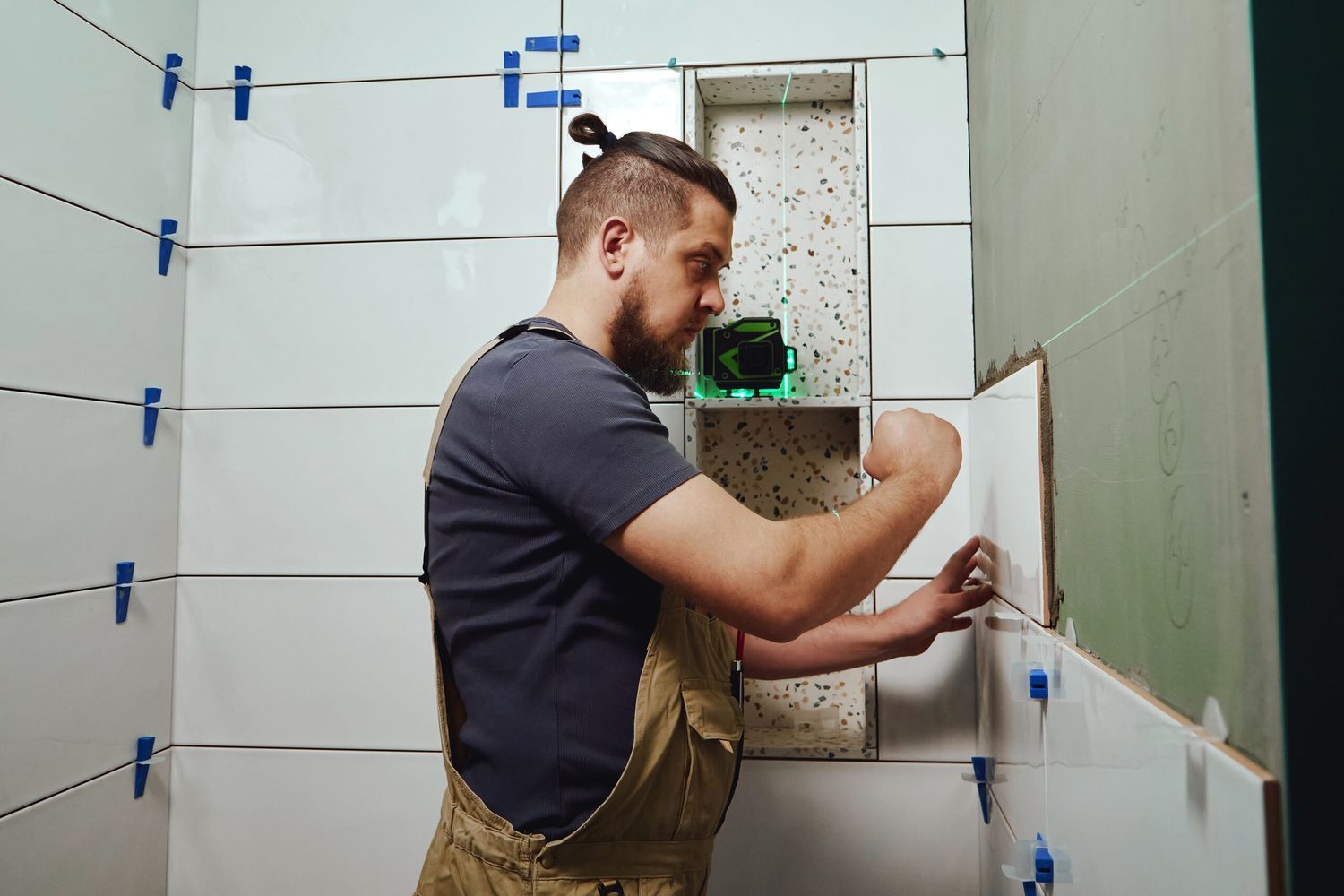 A man placing tiling over a cement backerboard.