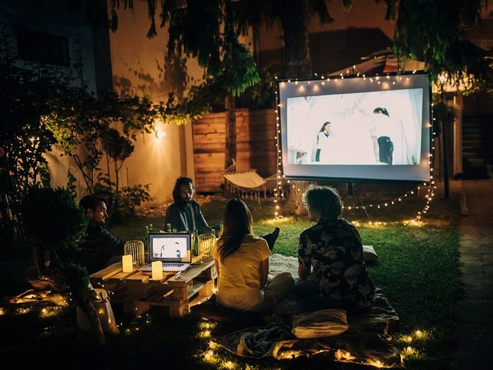 Friends watching movie on the video projector in the backyard garden