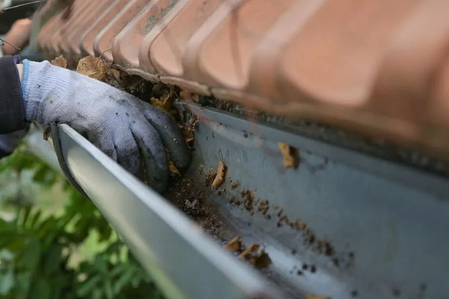 A man cleaning a gutter out by hand.