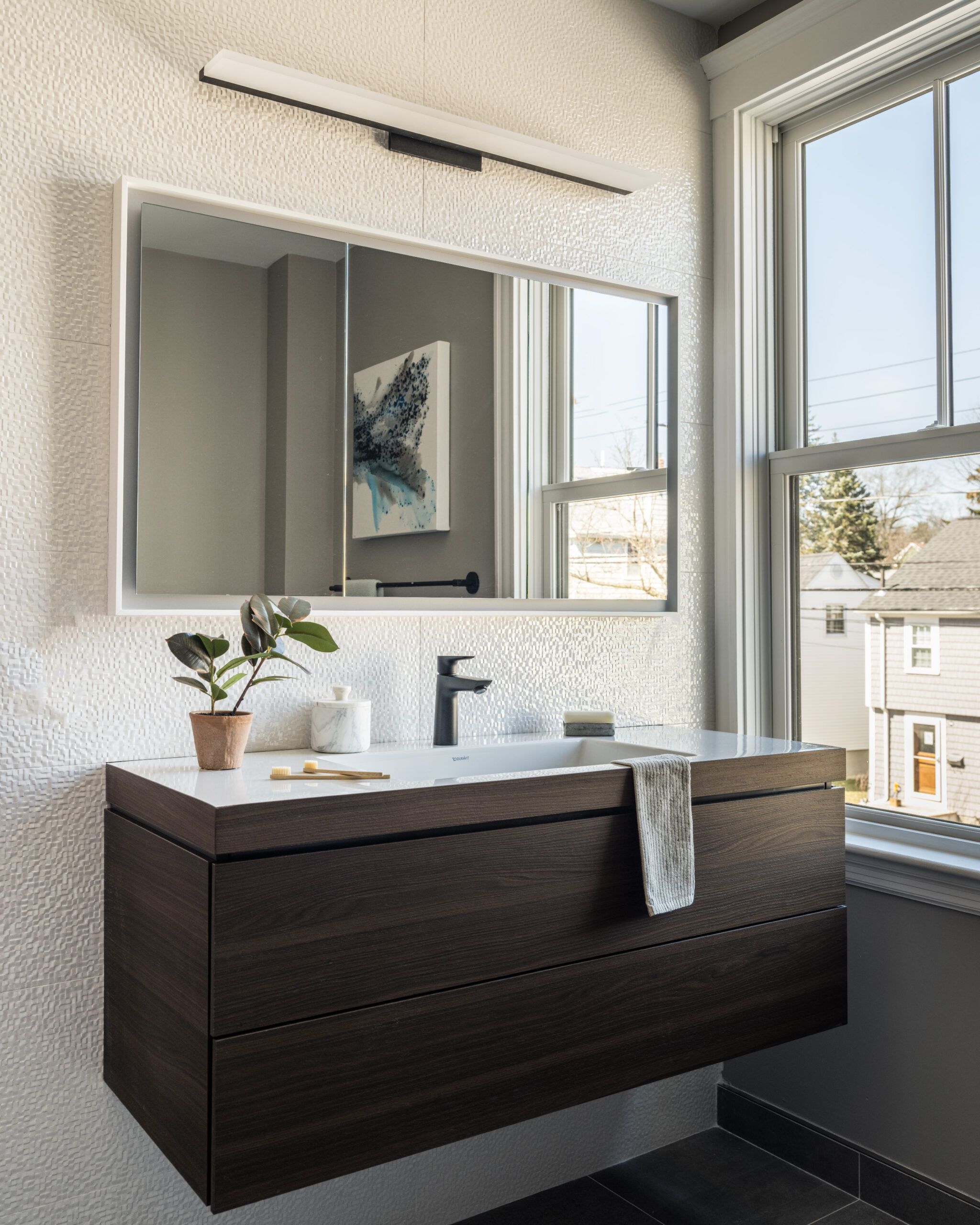 A small bathroom with a large mirror and wall mounted sink