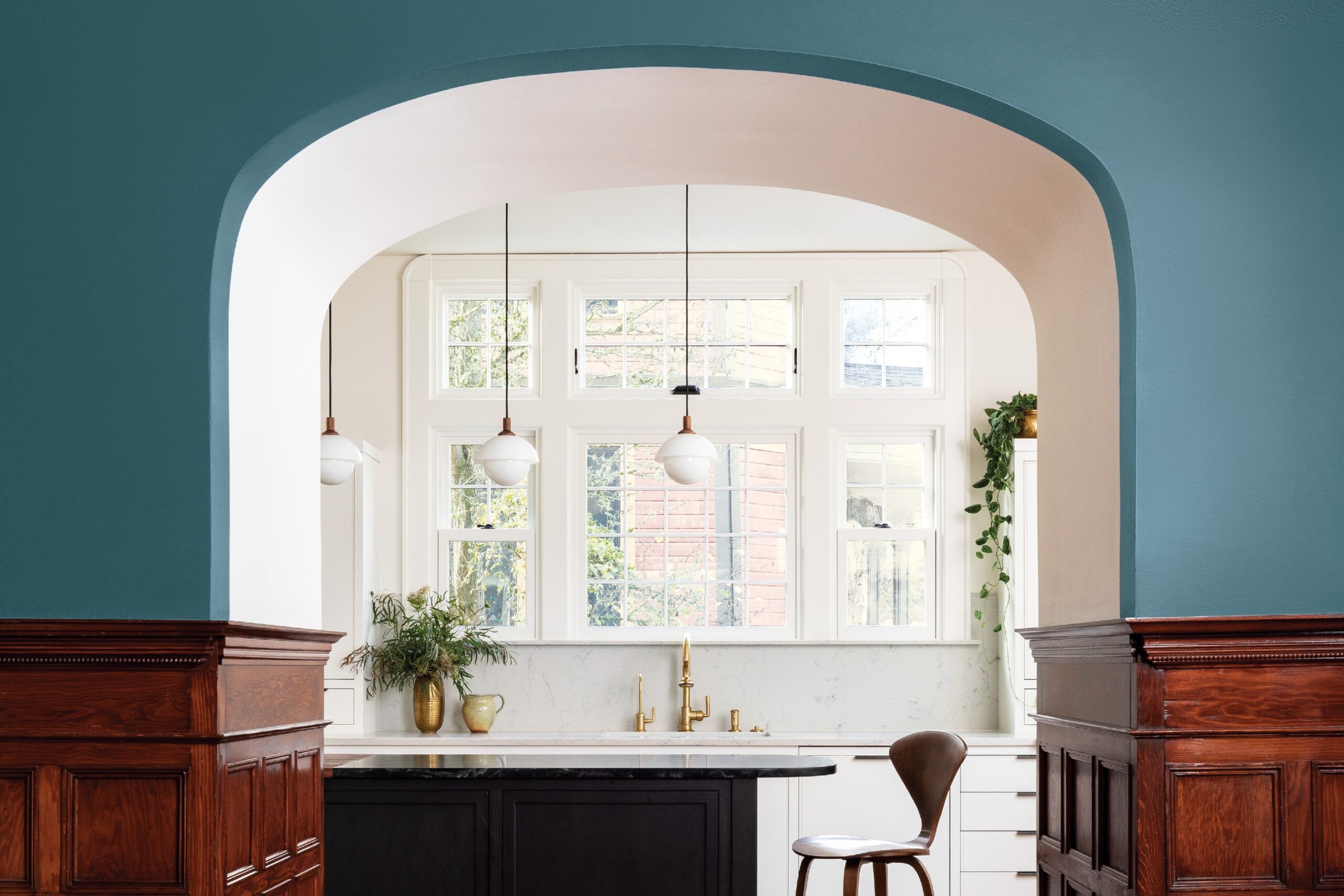 Arched hallway leading into a kitchen with a bold blue/green color