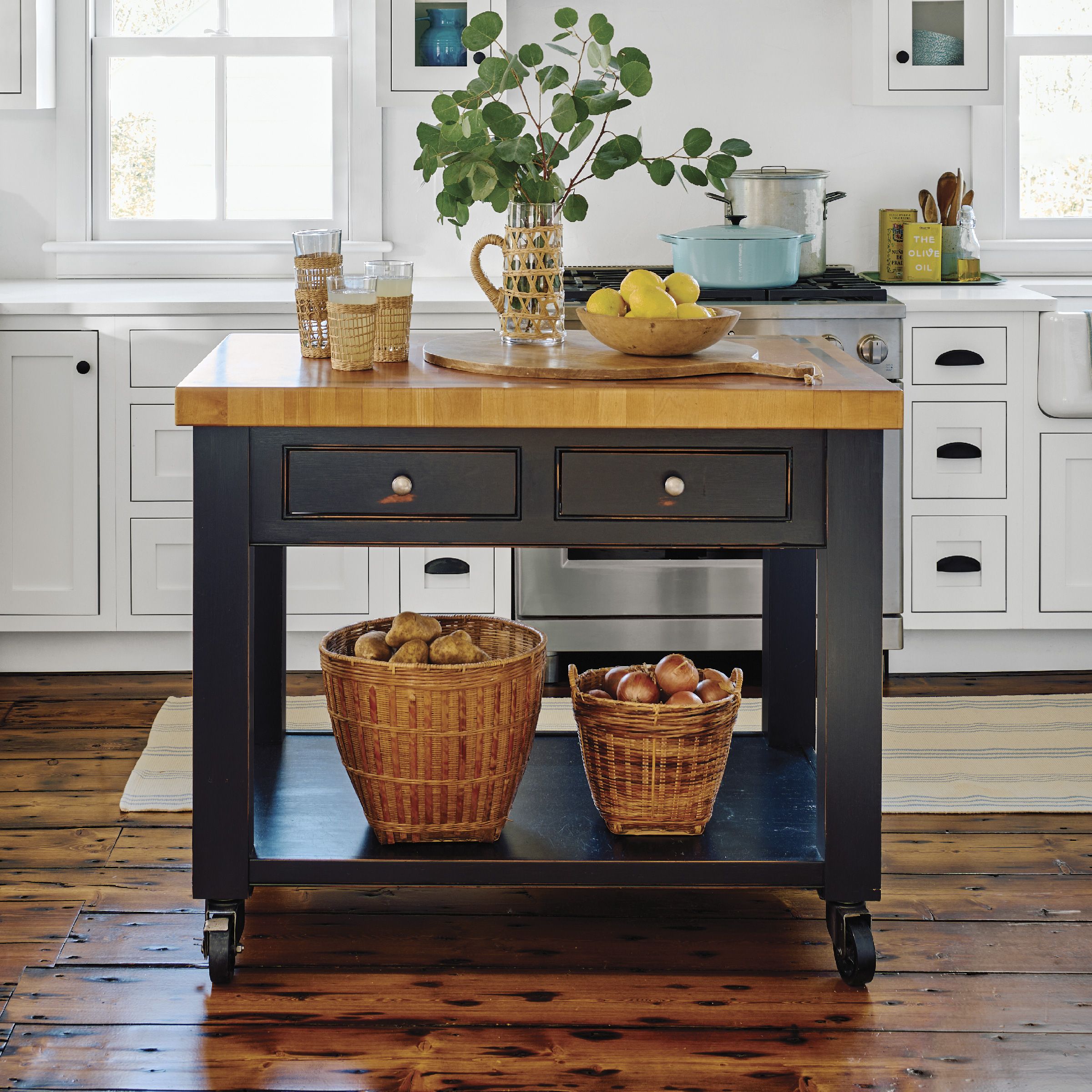 A kitchen island on wheels with a butcher block top.