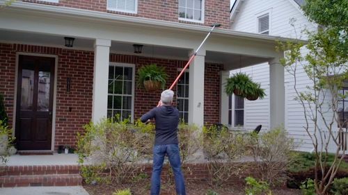 Man using gutter brush to clean gutters
