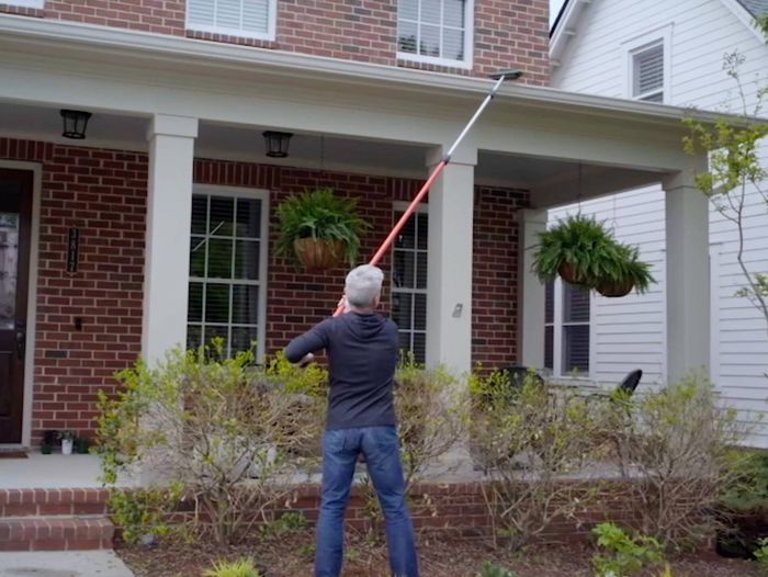 Man using gutter brush to clean gutters