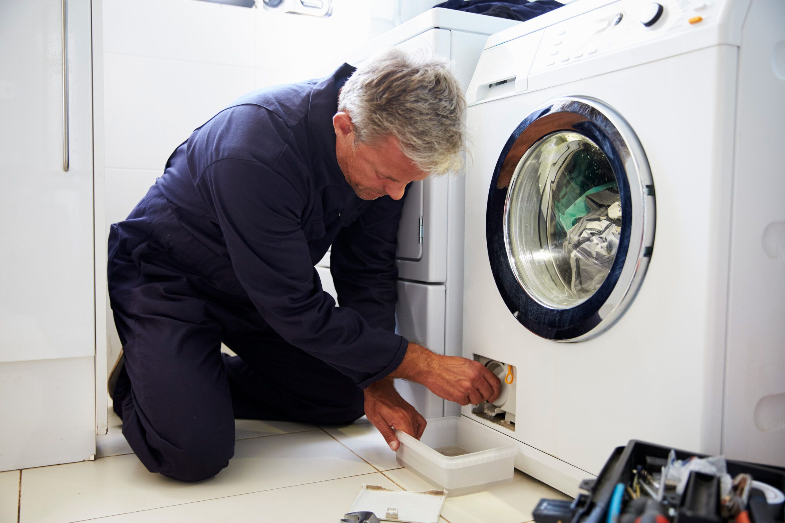 A plumber draining a front loading washer