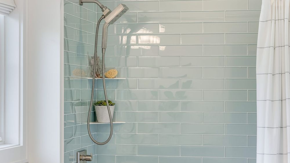 light blue tiled shower with handheld showerhead