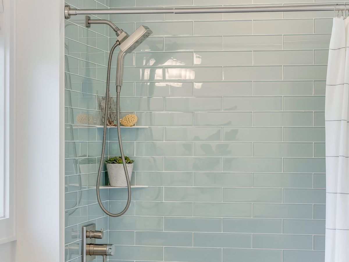 light blue tiled shower with handheld showerhead