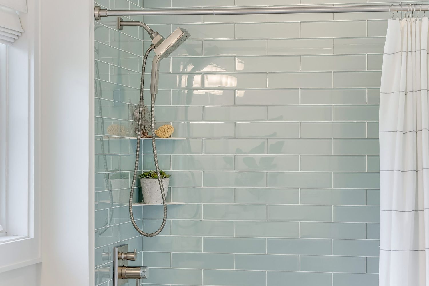 light blue tiled shower with handheld showerhead
