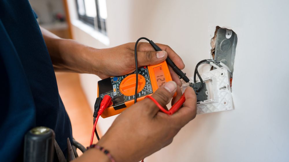 Close-up on an electrician fixing an electrical outlet and measuring the voltage at a house - home improvement concepts